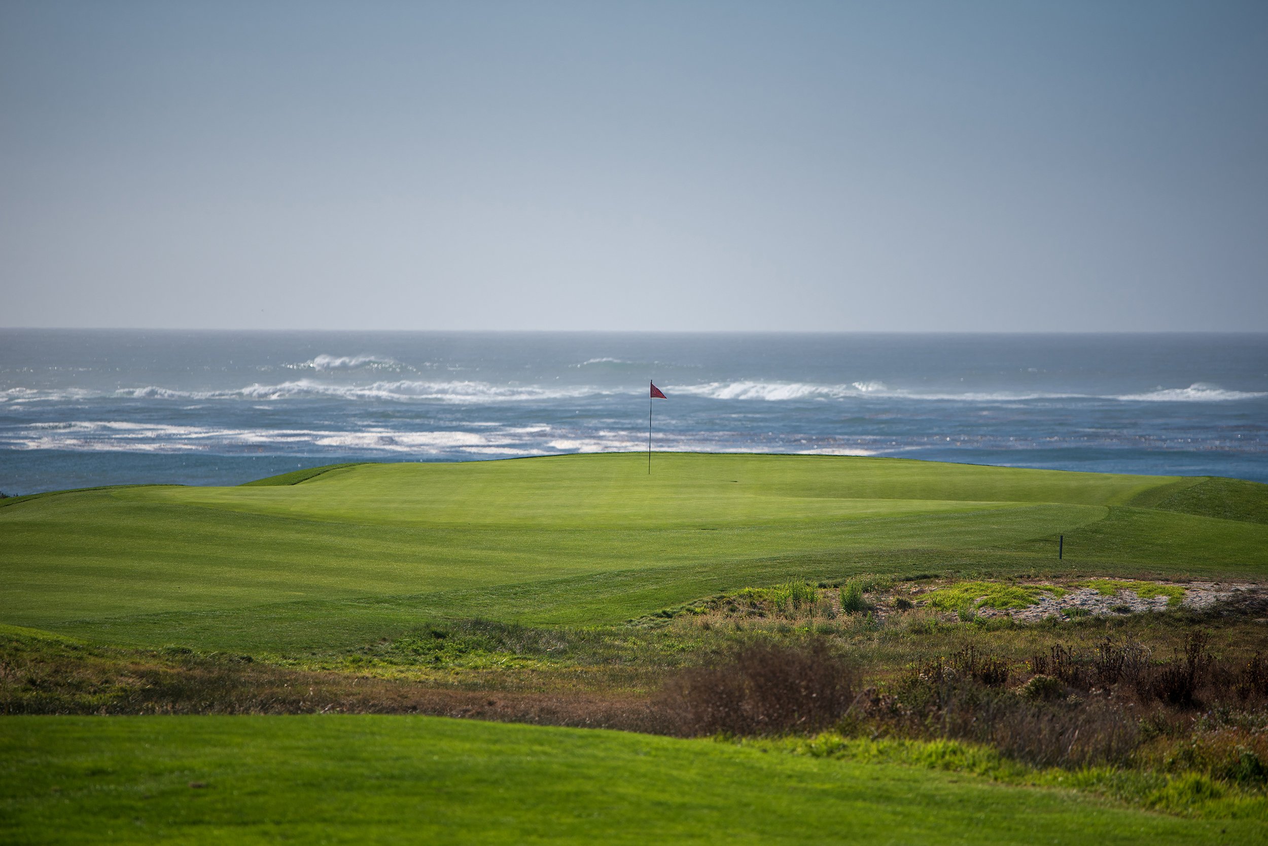 The first green at The Links at Spanish Bay from afar with the pacific ocean in the background