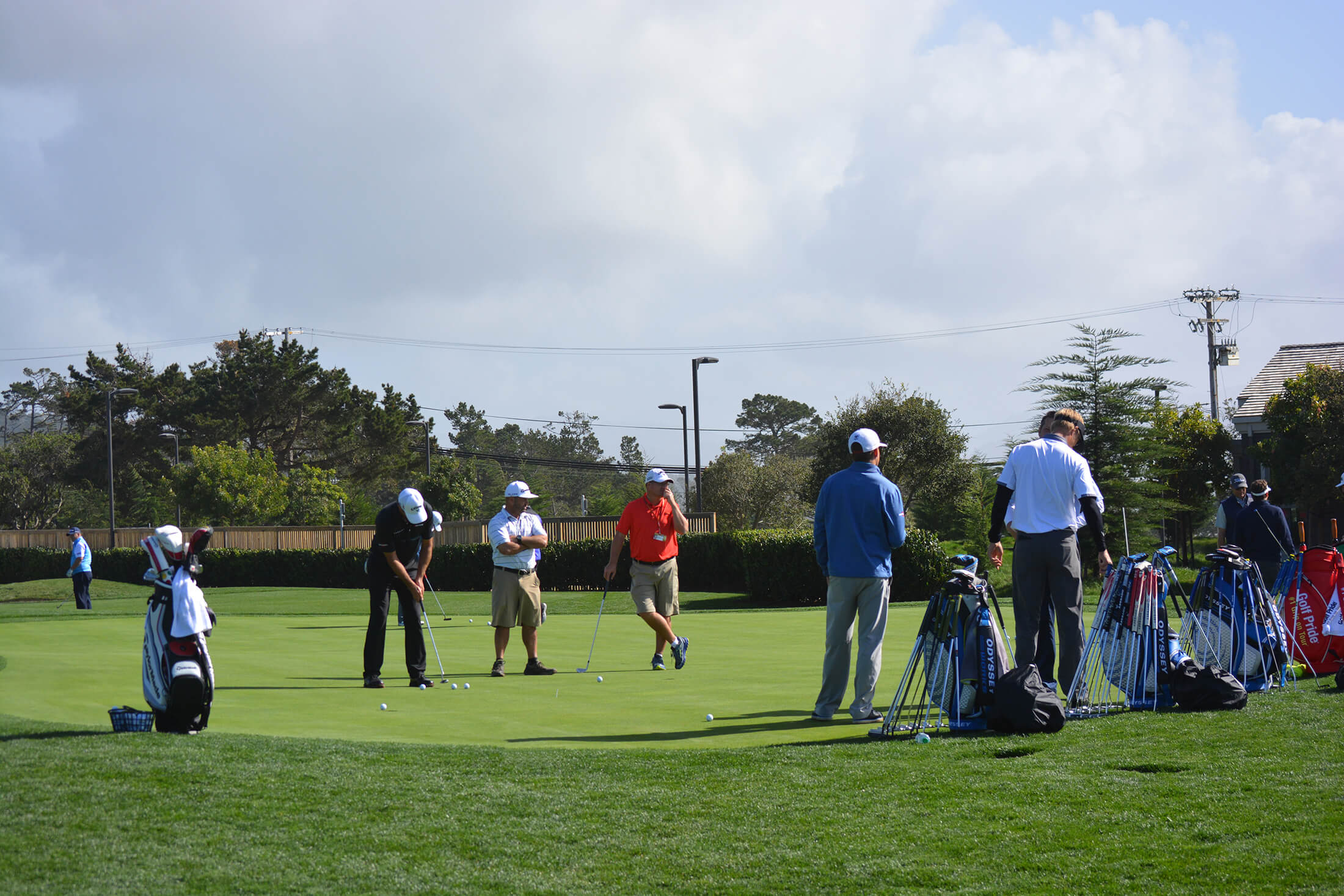 group of men stand around practicing their short game