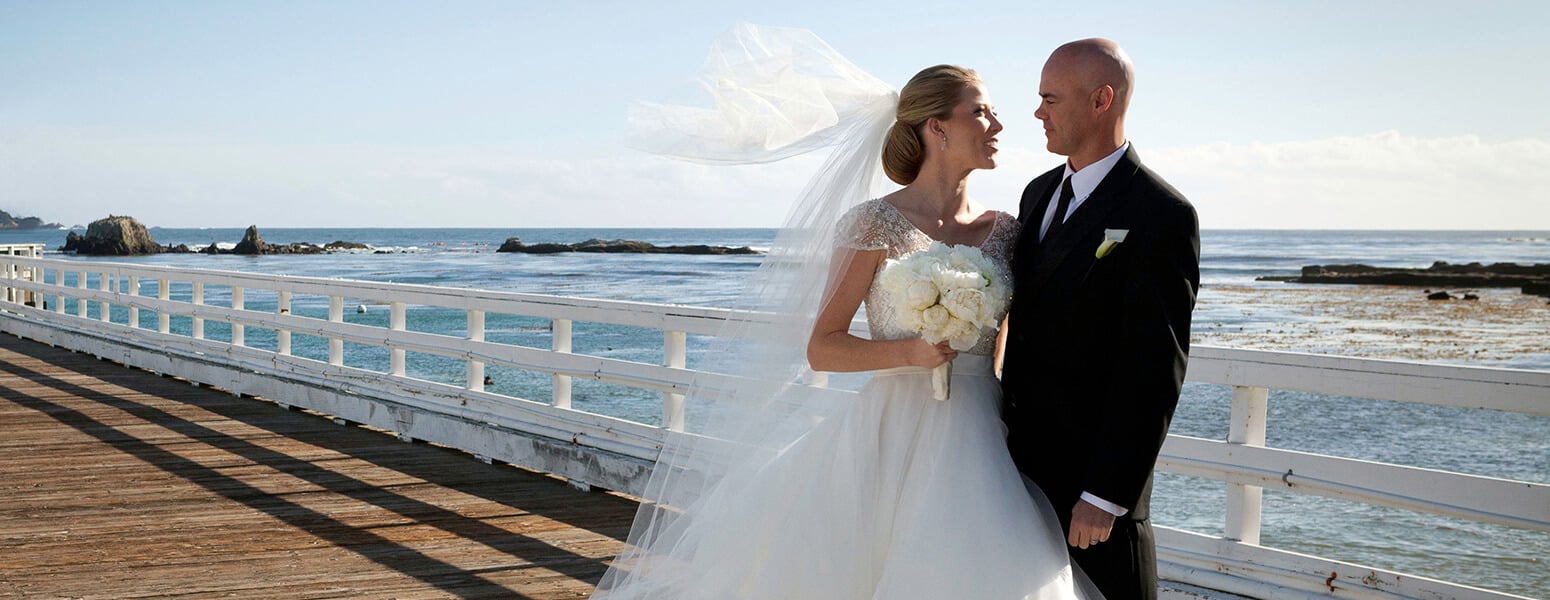 Bride and groom standing in front of the ocean
