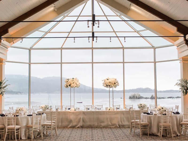 The Beach and Tennis Club dining room set for a wedding with long head table and tall flower arrangements