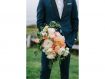 Groom holding bride's bouquet, garden roses in shades of pink with greenery.