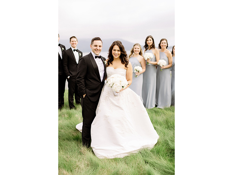 Smiling bride and groom with bridal party in background