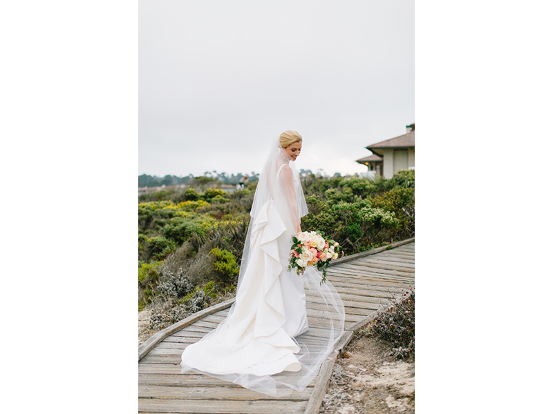 A bride at Spanish Bay with long veil and bouquet.